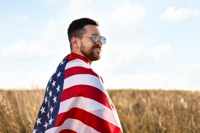 Happy man with flag of USA outdoors. Space for text