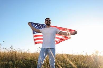 Happy man with flag of USA outdoors, low angle view