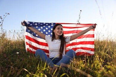 Photo of Happy woman with flag of USA sitting on grass outdoors