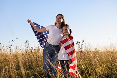 Photo of Happy mother and daughter with flag of USA outdoors