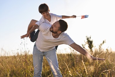 Happy father and son with flag of USA having fun outdoors