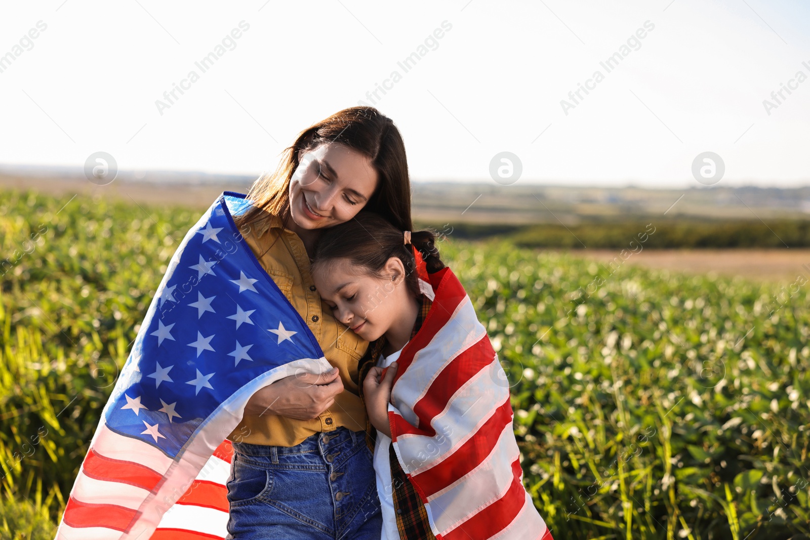 Photo of Happy mother and daughter with flag of USA outdoors. Space for text