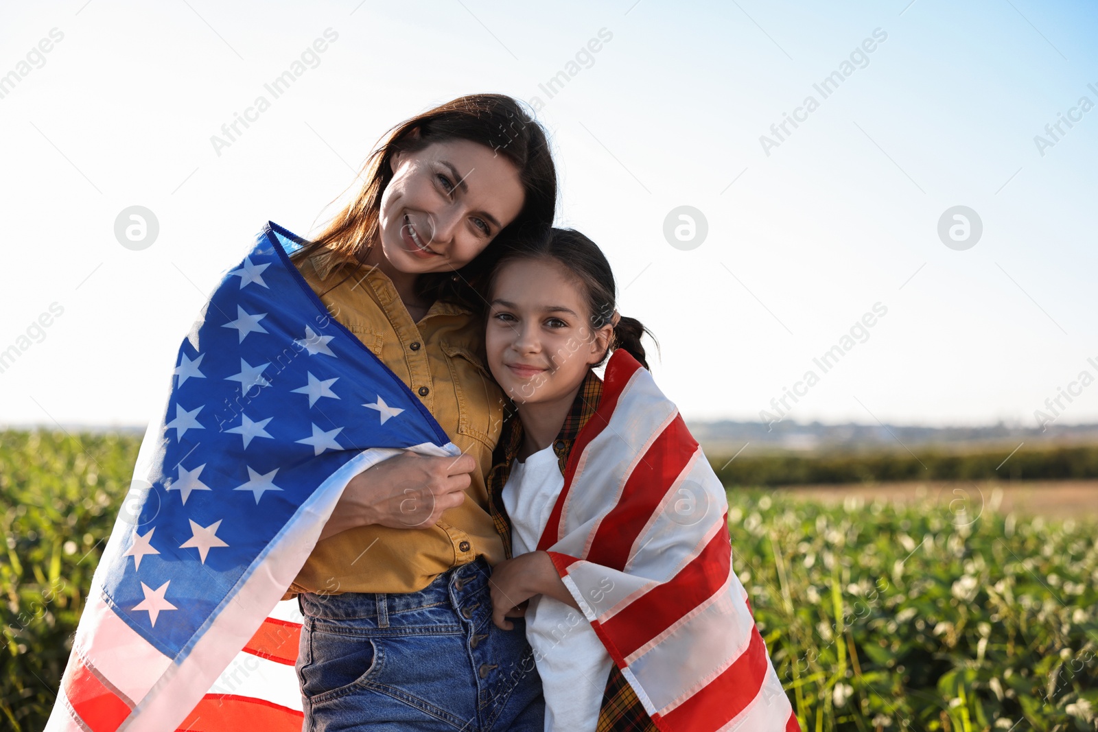 Photo of Happy mother and daughter with flag of USA outdoors. Space for text