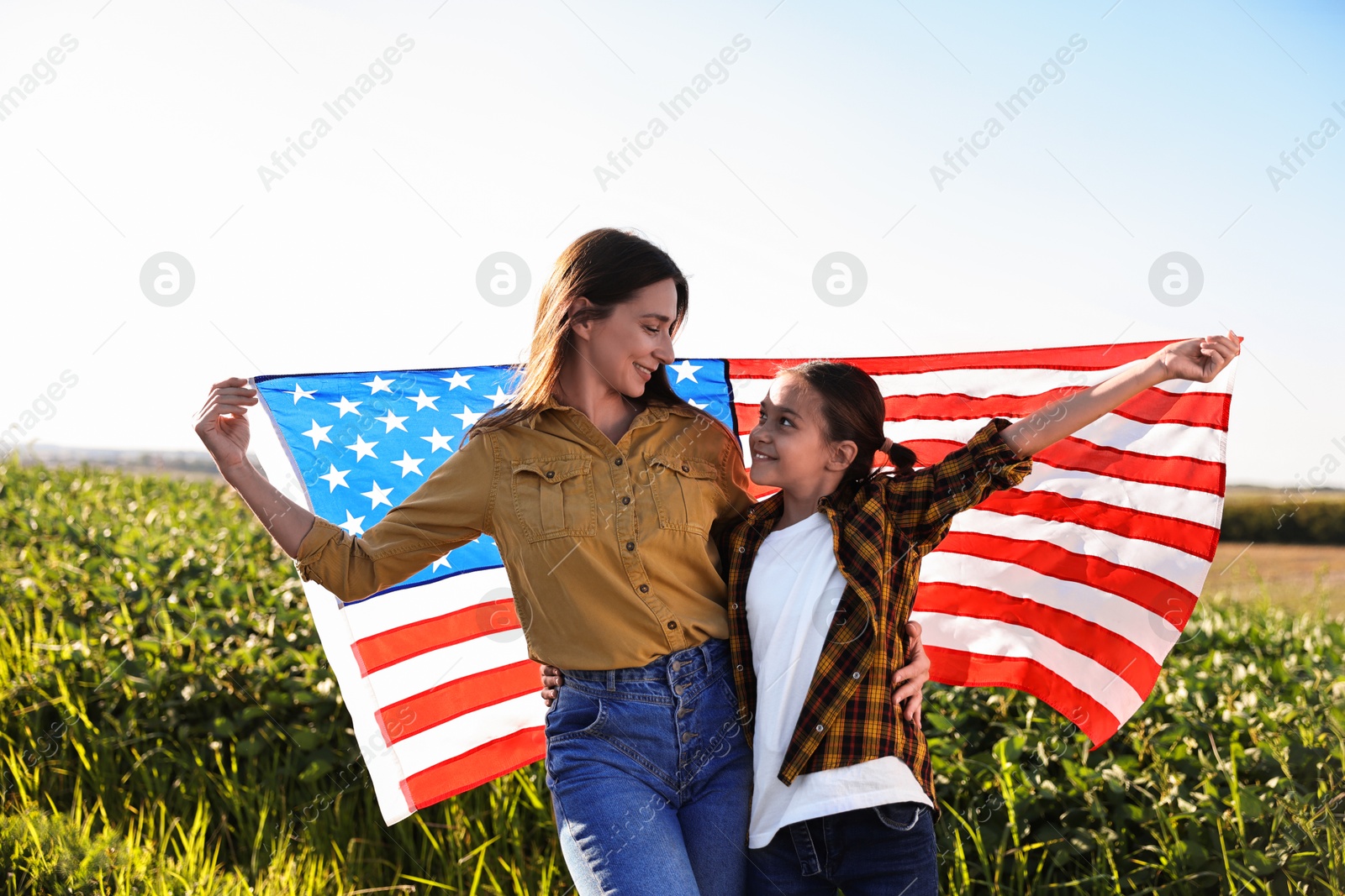 Photo of Happy mother and daughter with flag of USA outdoors