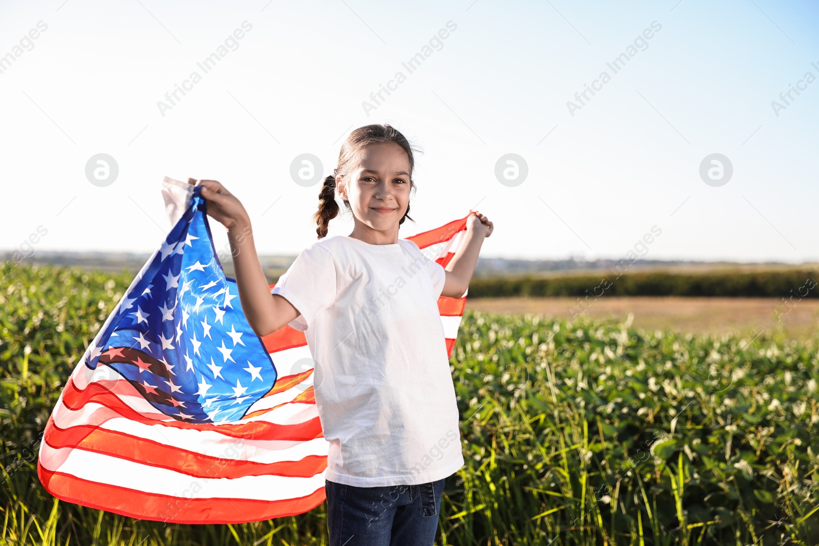 Photo of Little girl with flag of USA outdoors. Space for text