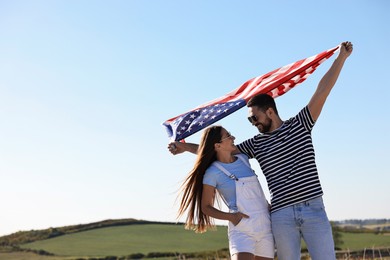 Photo of Happy couple with flag of USA outdoors. Space for text