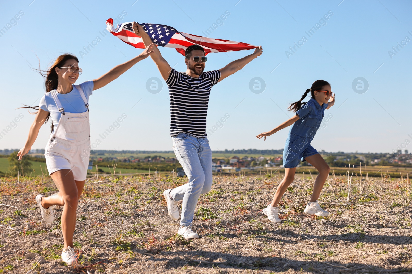 Photo of Happy family running with flag of USA outdoors