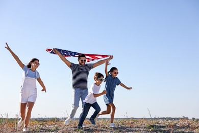 Photo of Happy family running with flag of USA outdoors. Space for text