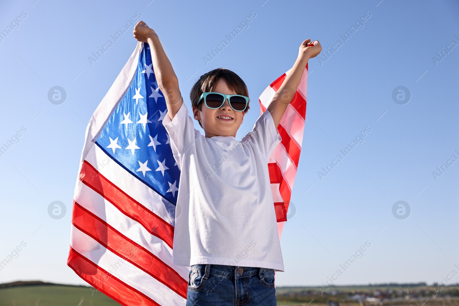 Photo of Portrait of happy boy with flag of USA outdoors