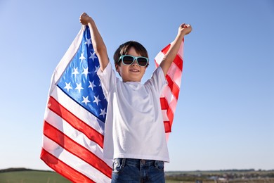 Portrait of happy boy with flag of USA outdoors