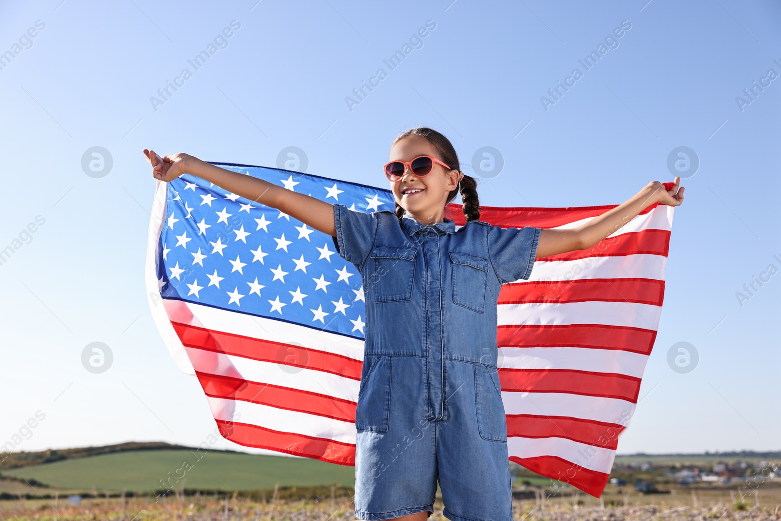 Photo of Happy girl with flag of USA outdoors