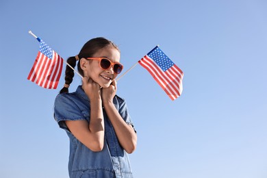 Photo of Happy girl with flags of USA outdoors. Space for text