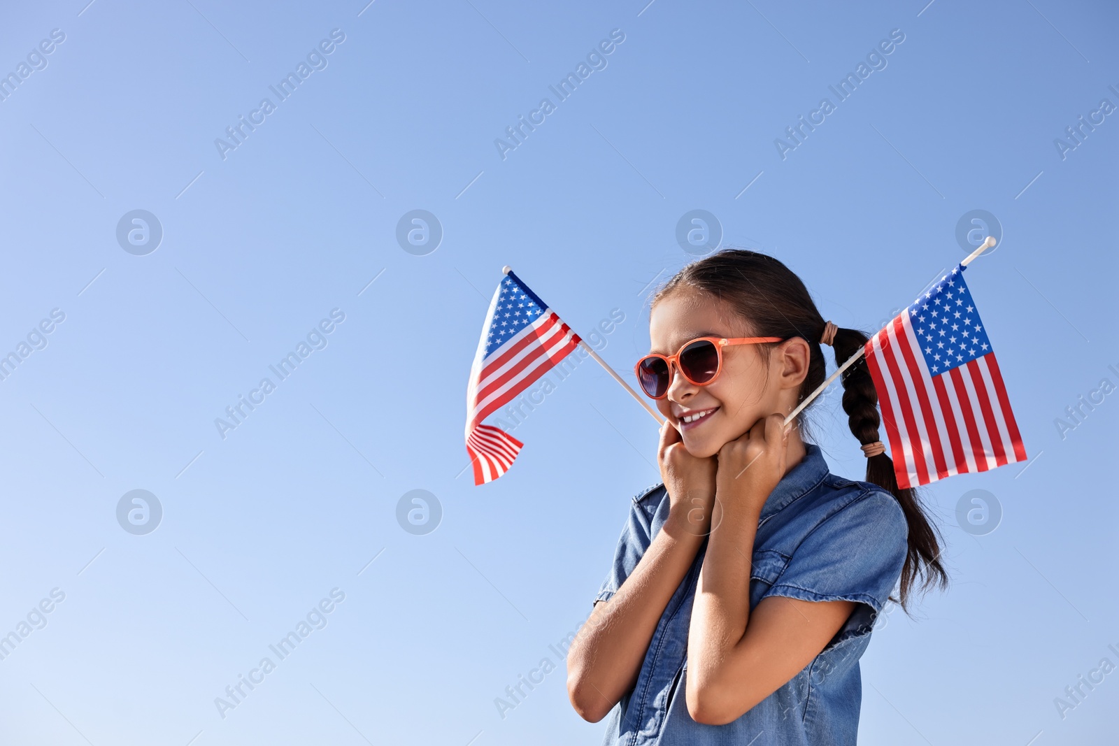 Photo of Happy girl with flags of USA outdoors. Space for text