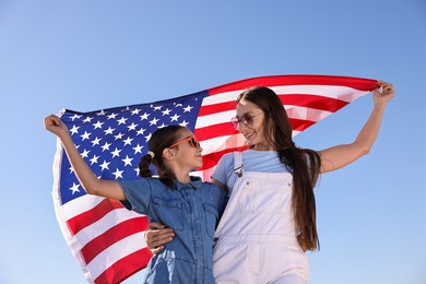 Happy mother and daughter with flag of USA outdoors