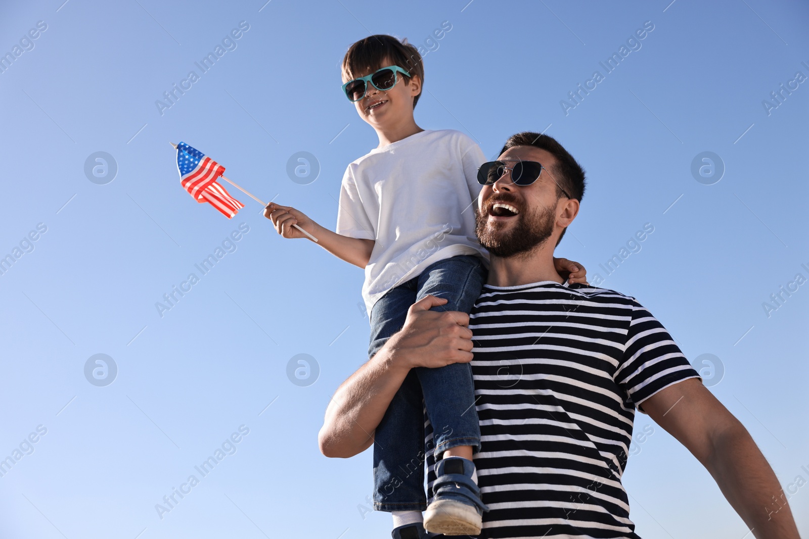 Photo of Happy father and son with flag of USA outdoors, low angle view