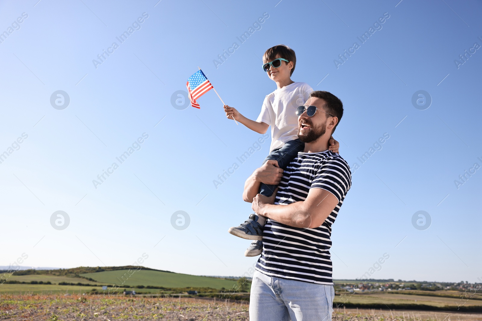 Photo of Happy father and son with flag of USA outdoors. Space for text