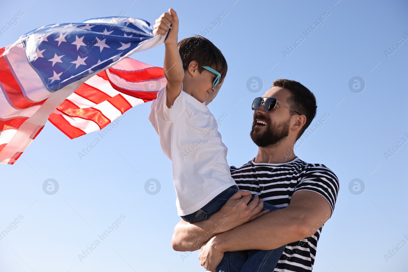 Photo of Happy father and son with flag of USA outdoors