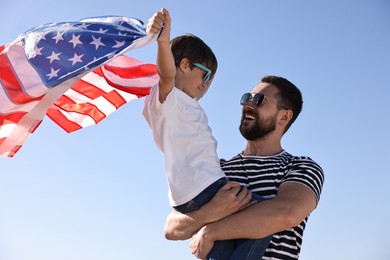 Happy father and son with flag of USA outdoors