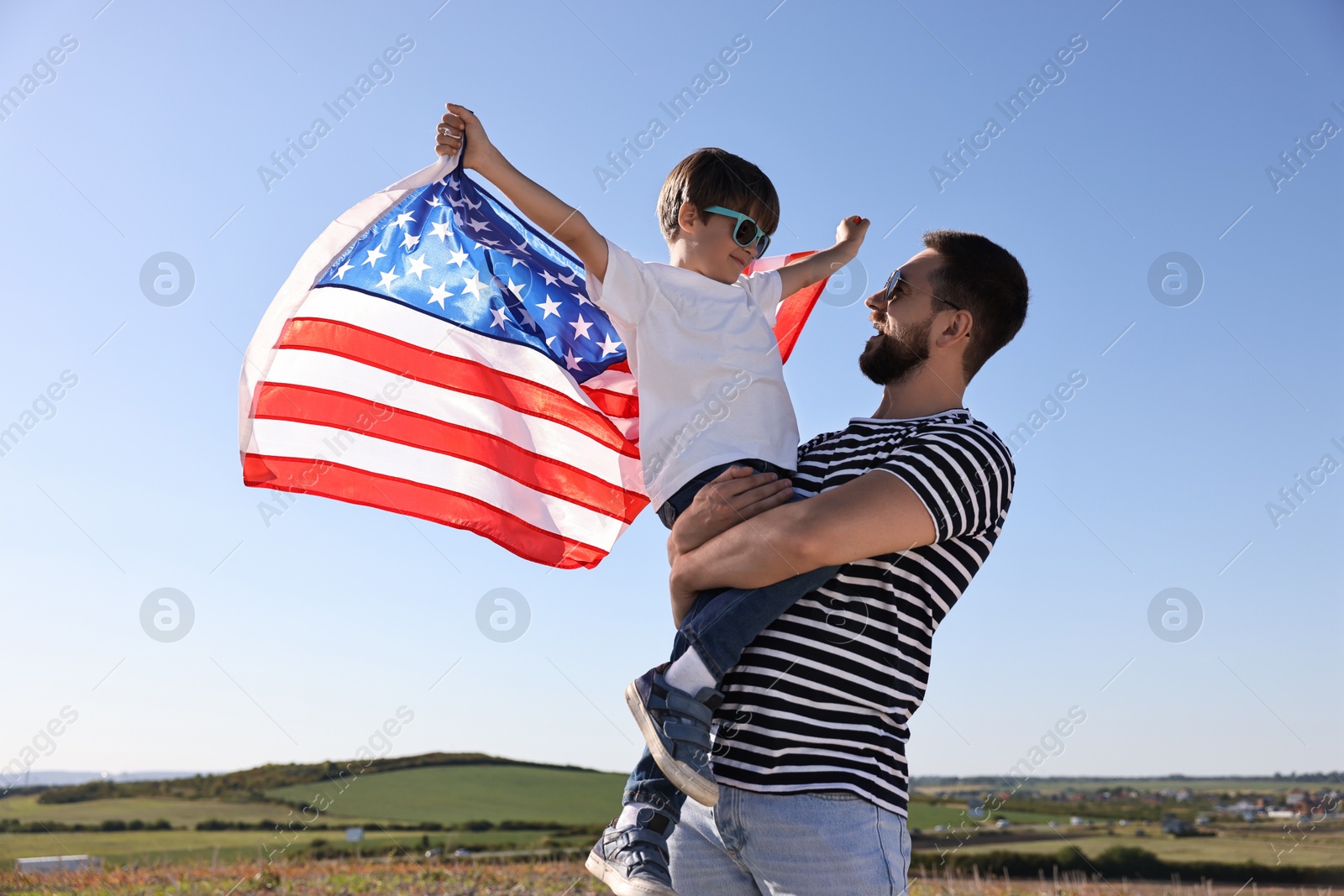 Photo of Happy father and son with flag of USA outdoors