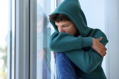 Photo of Loneliness concept. Sad teenage boy near window indoors