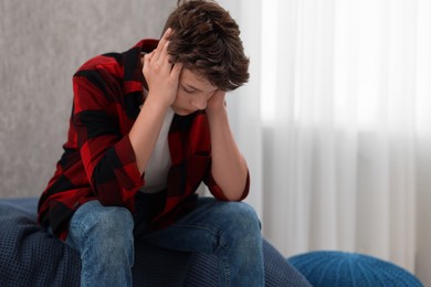 Photo of Loneliness concept. Sad teenage boy on bed at home, space for text