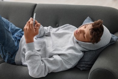 Loneliness concept. Sad teenage boy using smartphone on sofa at home