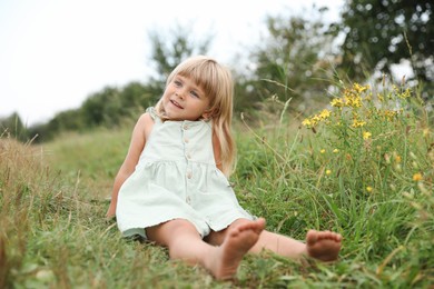 Photo of Barefoot little girl on green grass at meadow. Child enjoying beautiful nature