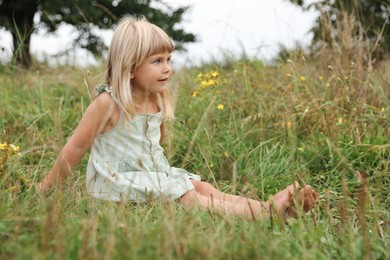 Photo of Barefoot little girl on green grass at meadow. Child enjoying beautiful nature