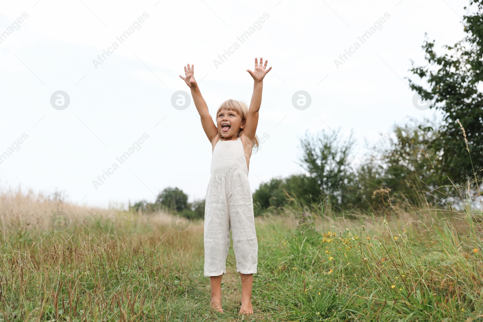 Photo of Cute little girl walking barefoot at meadow. Child enjoying beautiful nature