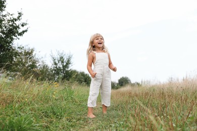 Cute little girl walking barefoot at meadow. Child enjoying beautiful nature