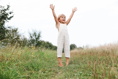 Photo of Cute little girl walking barefoot at meadow. Child enjoying beautiful nature