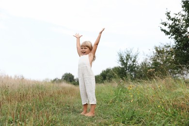 Cute little girl walking barefoot at meadow. Child enjoying beautiful nature