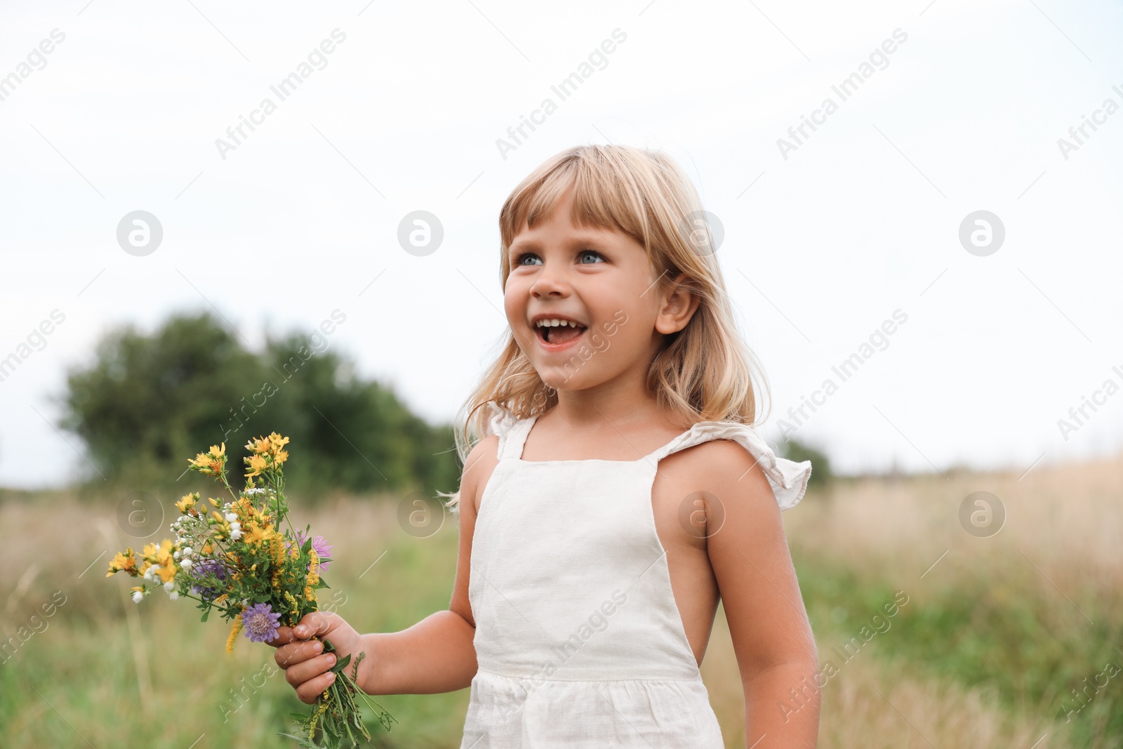 Photo of Cute little girl with flowers at meadow. Child enjoying beautiful nature