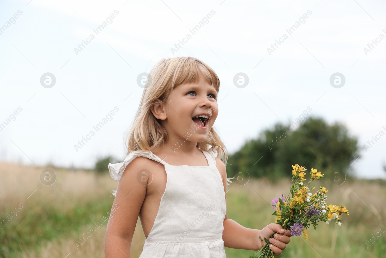 Photo of Cute little girl with flowers at meadow. Child enjoying beautiful nature