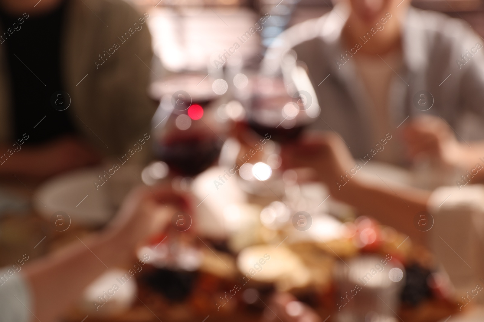 Photo of Blurred view of people clinking glasses with wine, closeup