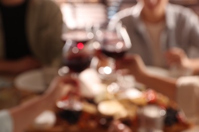 Photo of Blurred view of people clinking glasses with wine, closeup