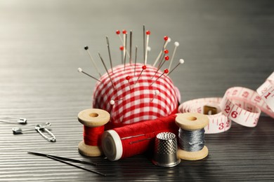 Photo of Different sewing tools on wooden table, closeup