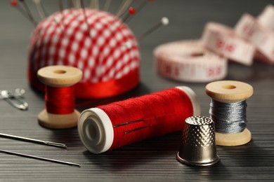 Different sewing tools on wooden table, closeup