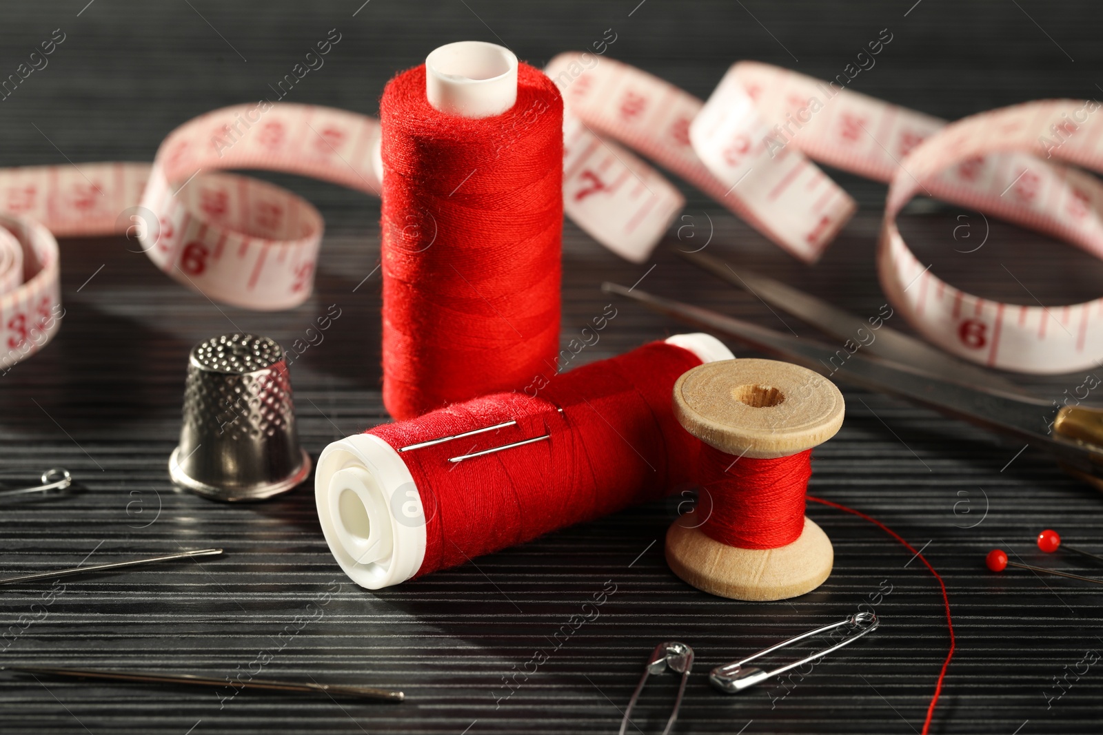 Photo of Different sewing tools on wooden table, closeup