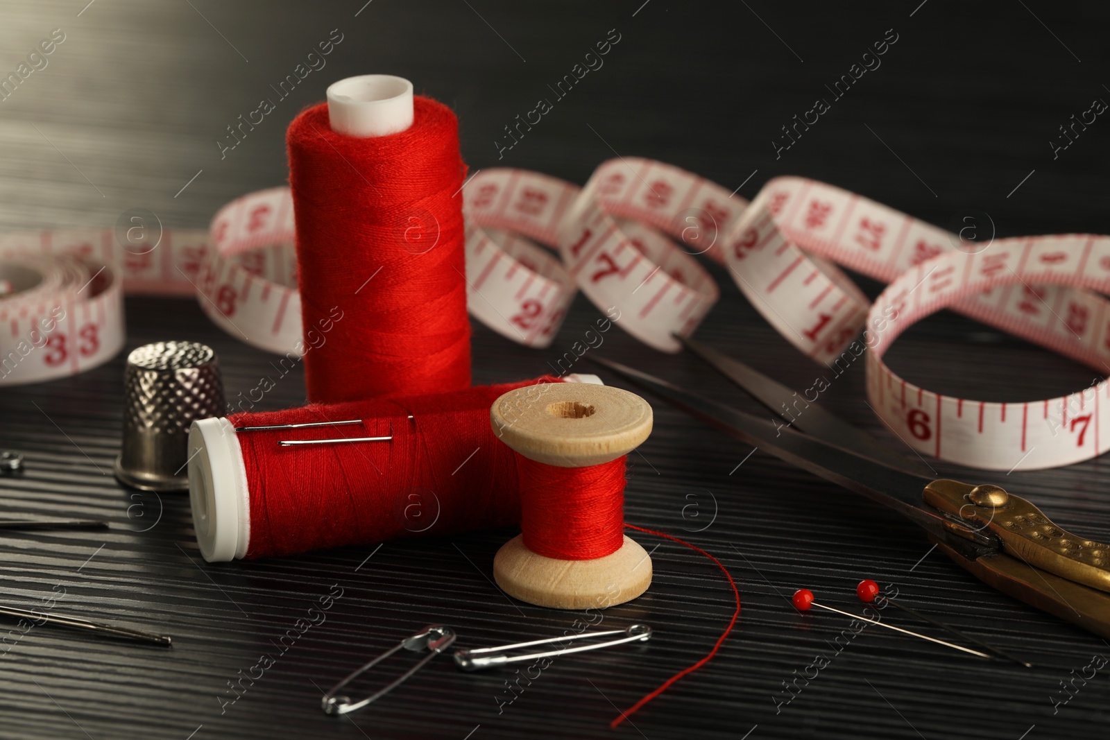 Photo of Different sewing tools on wooden table, closeup