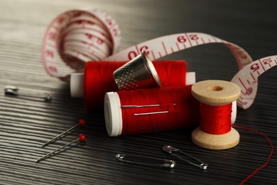 Photo of Different sewing tools on wooden table, closeup