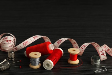 Photo of Different sewing tools on wooden table. Space for text