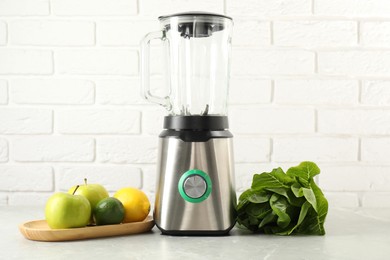 Photo of Blender and products on light table against white brick wall