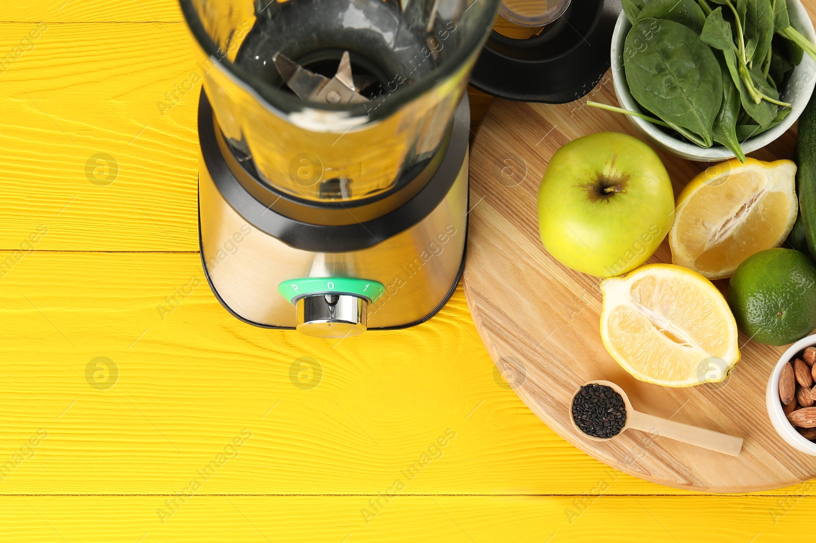 Photo of Modern blender with ingredients for smoothie on yellow wooden table, above view