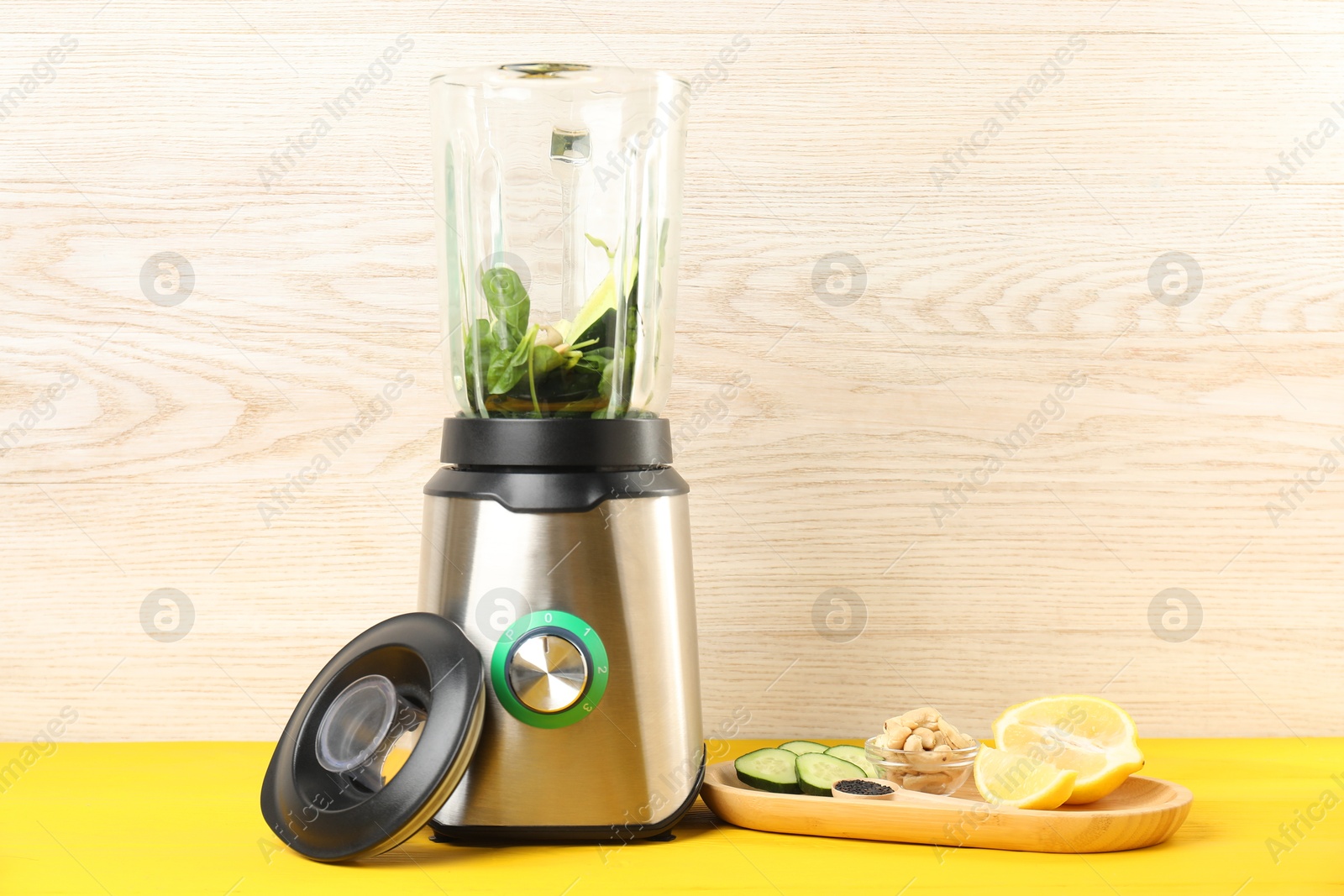 Photo of Modern blender with ingredients for smoothie on yellow wooden table. Space for text