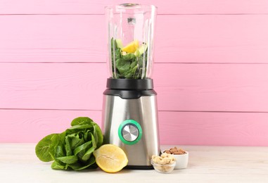 Photo of Modern blender with ingredients for smoothie on white wooden table