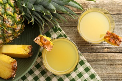 Photo of Tasty pineapple juice in glasses and fresh fruit on wooden table, flat lay