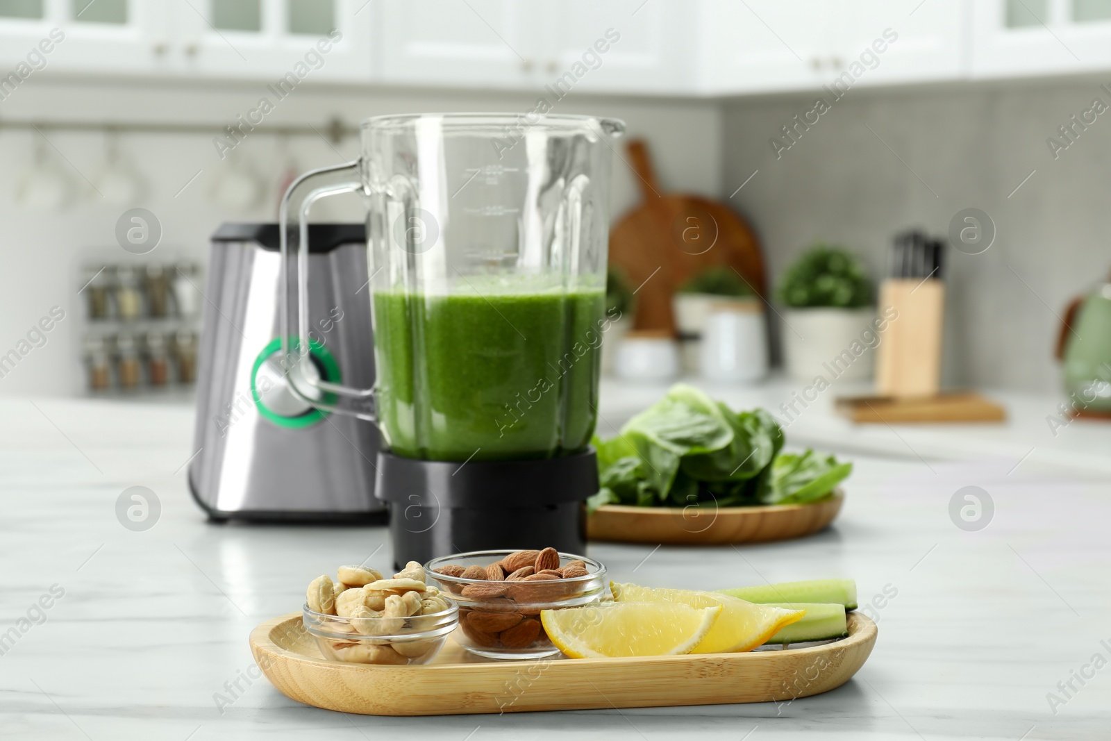 Photo of Modern blender with smoothie and ingredients on white marble table in kitchen