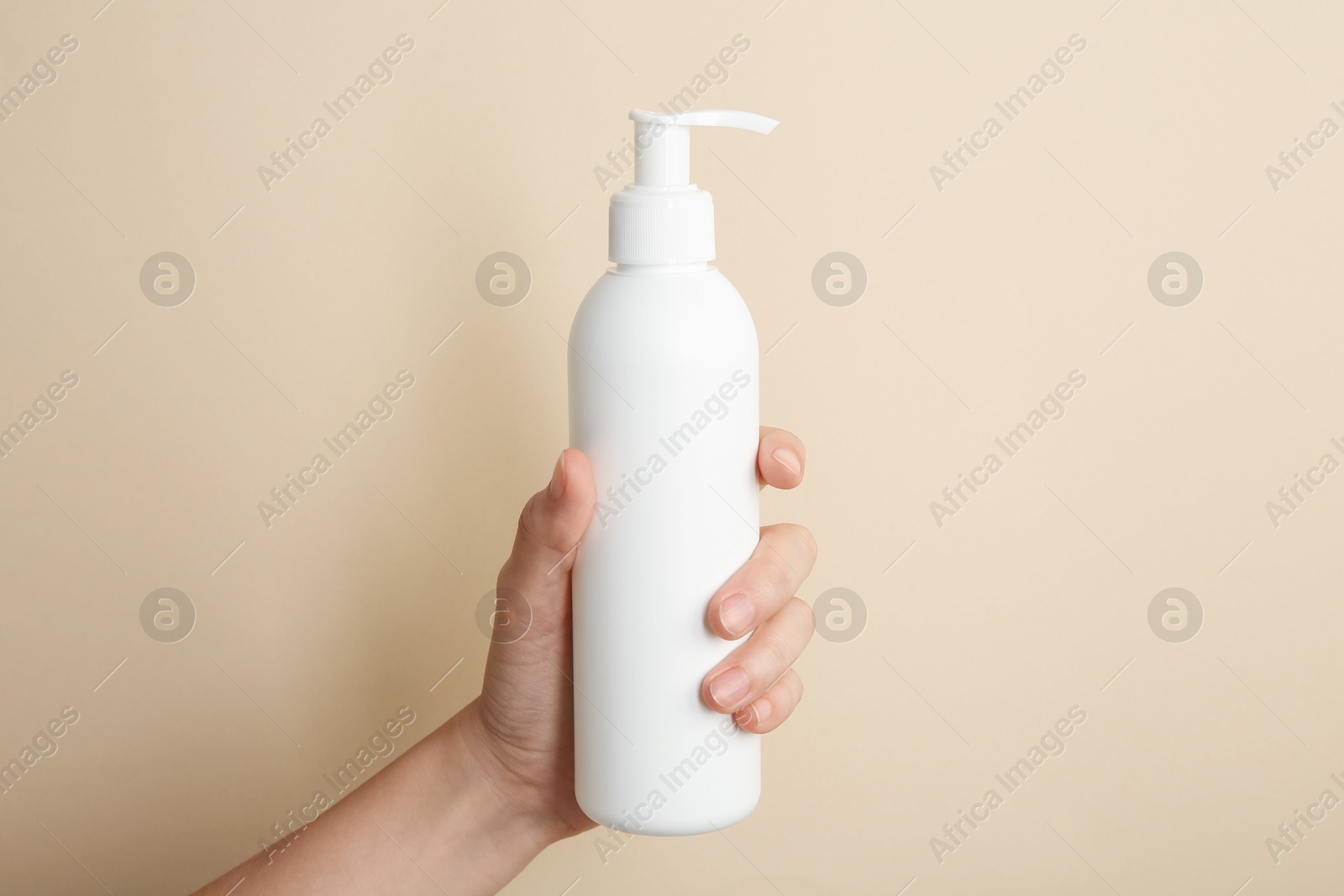 Photo of Woman with shampoo bottle on beige background, closeup