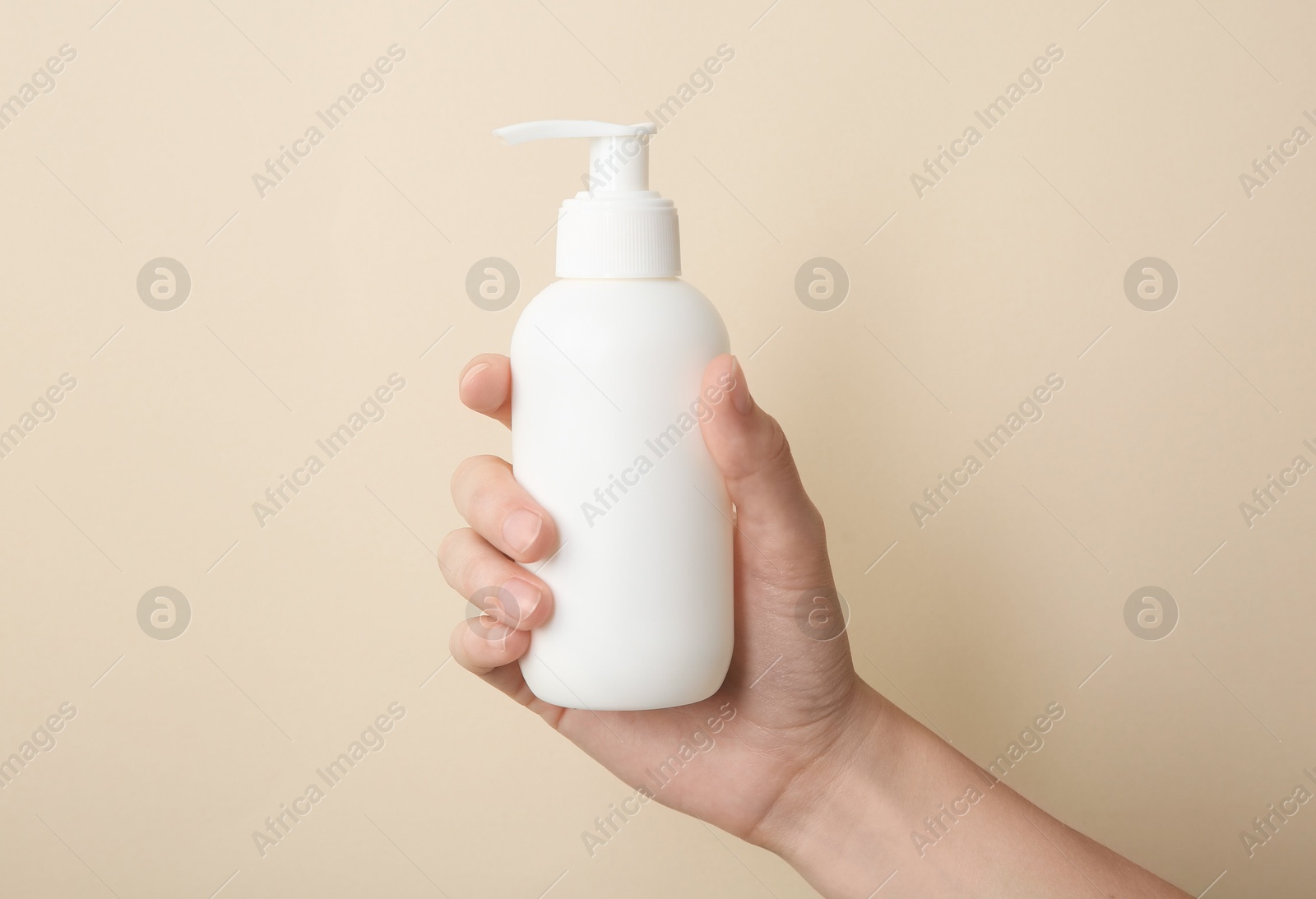 Photo of Woman with shampoo bottle on beige background, closeup